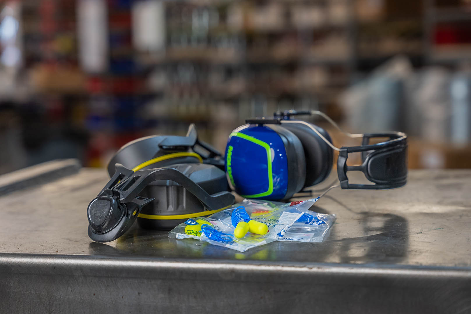 Earplugs and Hearing Protection Hearing protection earmuffs and ear plugs for noise reduction in industrial environments, shown on a metal workbench at PT Hose & Bearing.