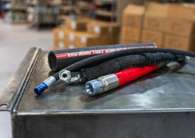 Rotary hydraulic drilling hose for high-pressure fluid transfer in drilling operations, shown on a metal workbench at PT Hose & Bearing.