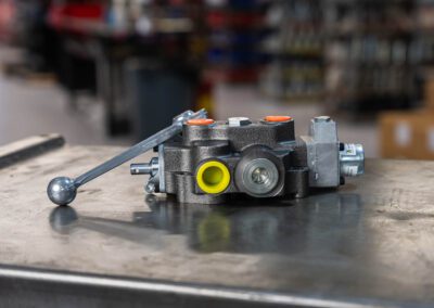 Hydraulic valve for controlling fluid flow in industrial systems, shown on a metal workbench at PT Hose & Bearing.