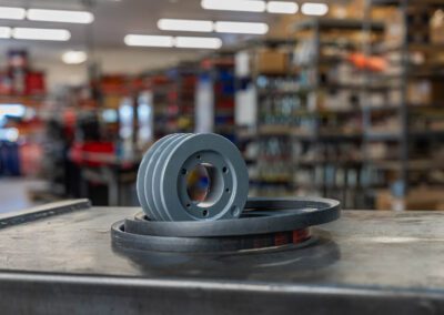 Industrial V-belt sheave and belts on a metal workbench in a warehouse setting at PT Hose & Bearing.